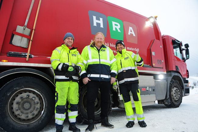 Tre renovatører ikledd arbeidsutstyr foran rød renovasjonsbil fra HRA.