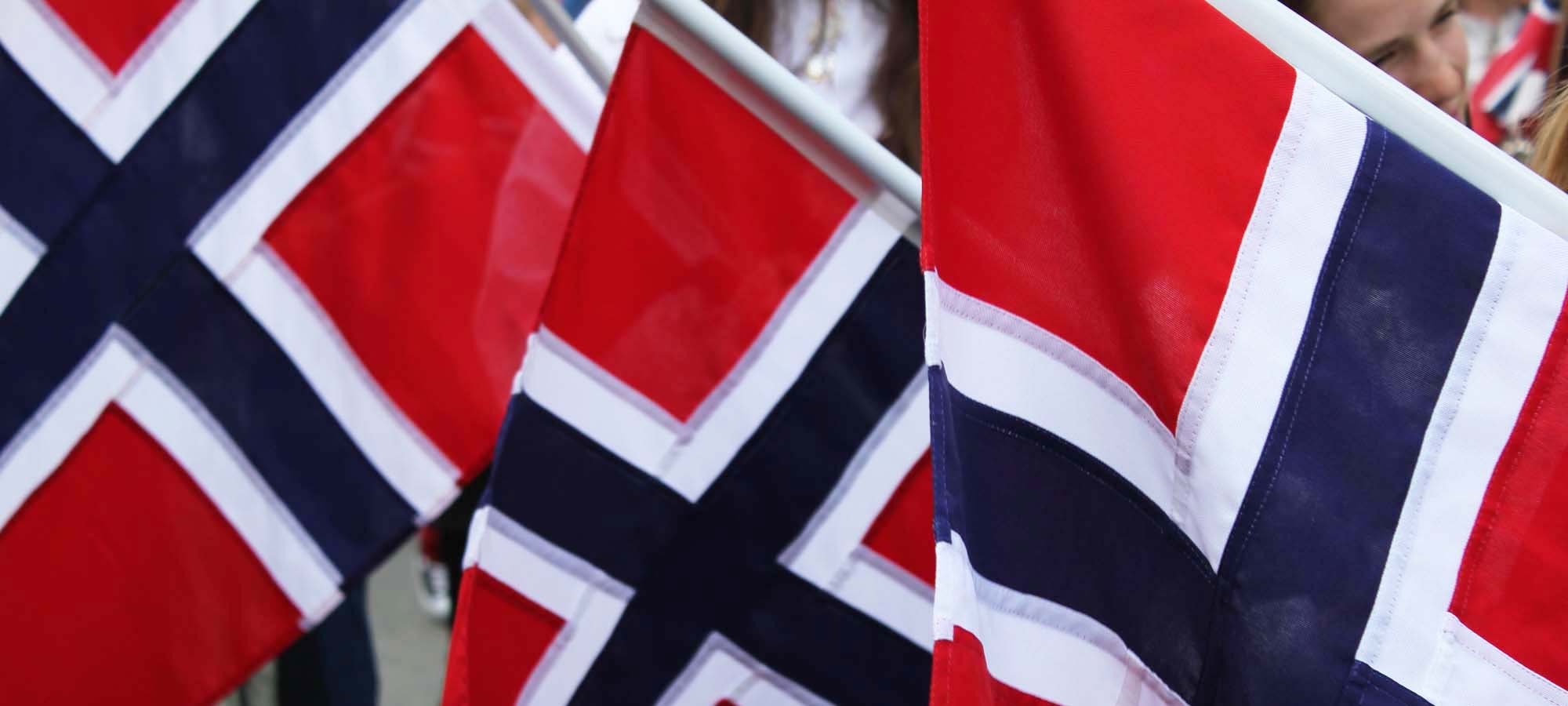 Norsk flagg i rødt hvitt og blått, vaier i vinden.